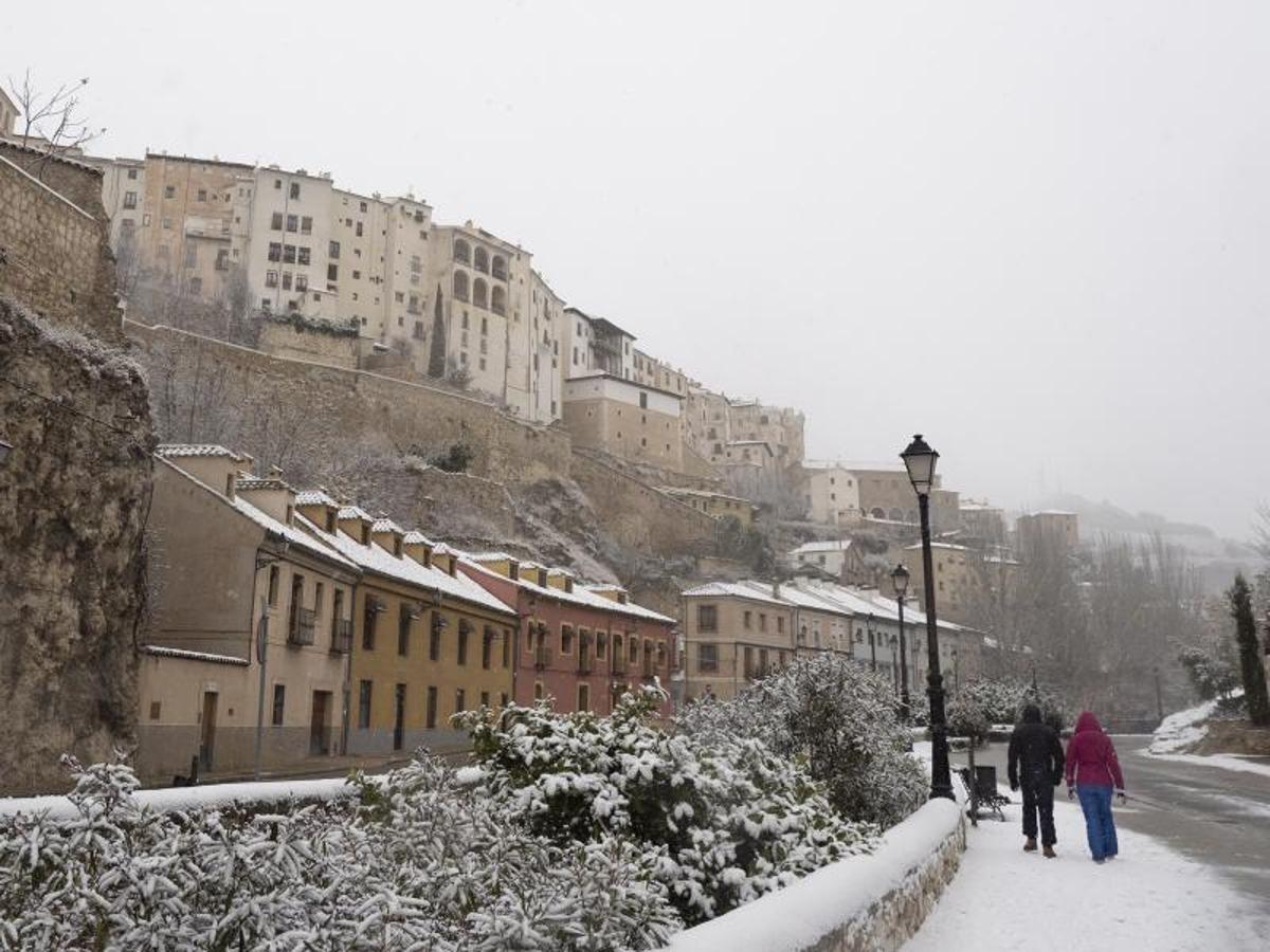 Dos viandantes pasean por Cuenca durante la nevada de este jueves.