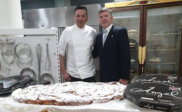 El delegado de la Hermandad Nacional Monárquica de España en Baleares y el pastelero junto a la ensaimada que recibirá el Rey.