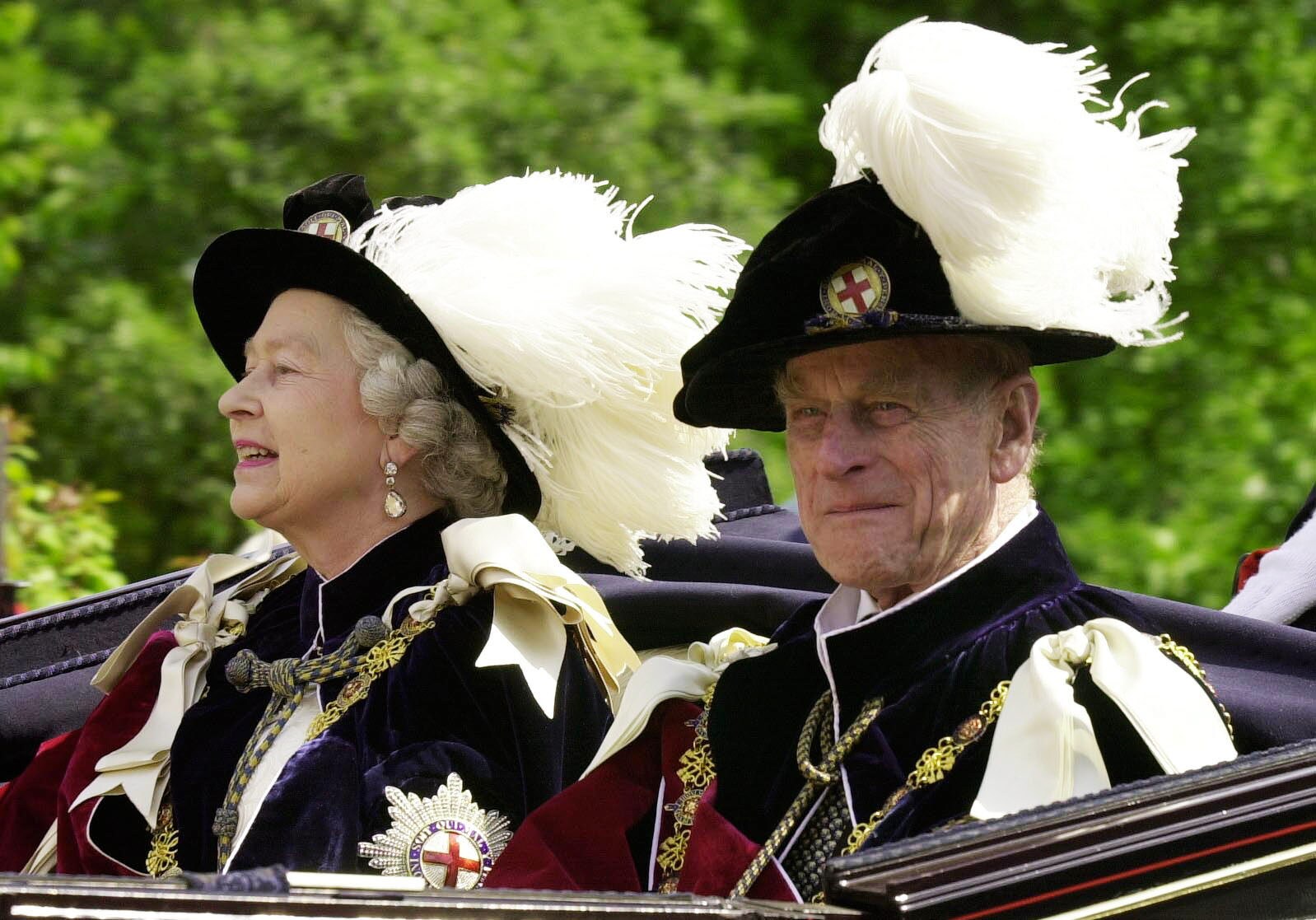 La reina Isabel y el duque de Edimburgo, vestidos con sus túnicas de la Orden de la J en arretera, viajan en un carruaje descubierto hasta el castillo de Windsor en junio de 2001.