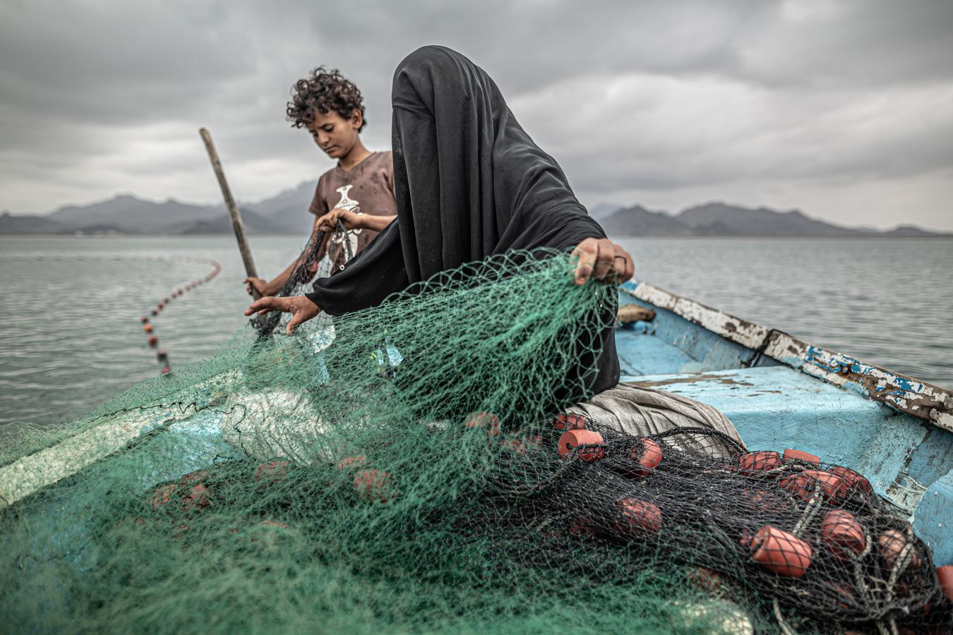 Categoría de temas contemporáneos. Una mujer y su hijo preparan una red de pesca en Yemen. 