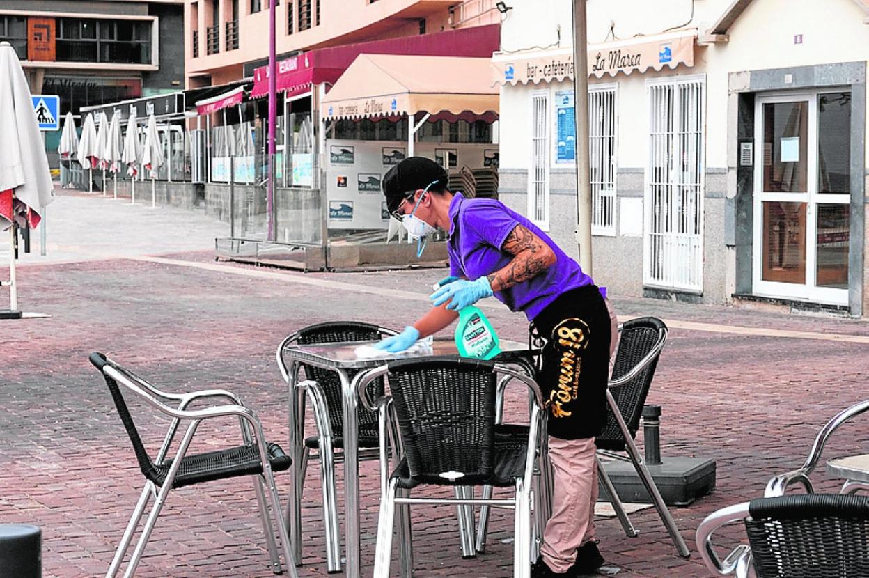 Un trabajador de un negocio desinfecta una mesa. 