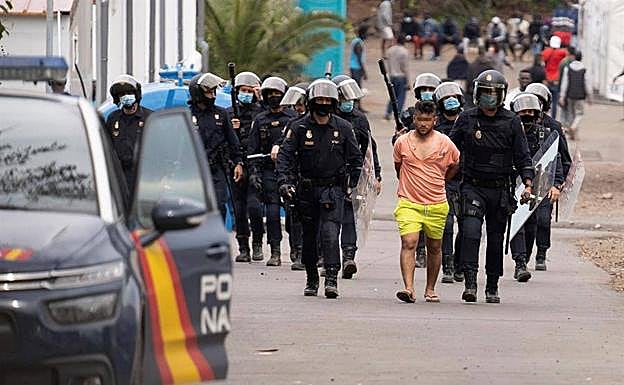 Policías antidisturbios trasladan a un detenido del campamento humanitario de Las Raíces tras los altercados ocurridos 