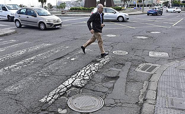 Una persona cruza un paso de peatones afectado por baches, en una imagen de 2018. 