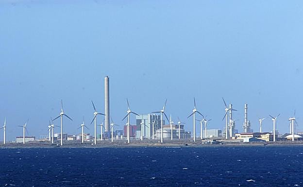 Vista de la central térmica de generación eléctrica Juan Grande rodeada de aerogeneradores. 