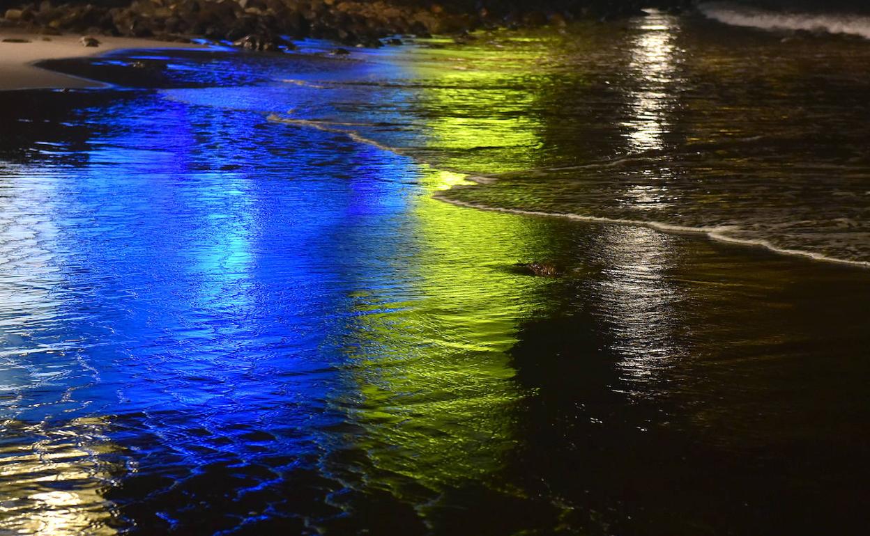 La bandera canaria proyectada en el Alfredo Kraus reflejada en la orilla de Las Canteras 