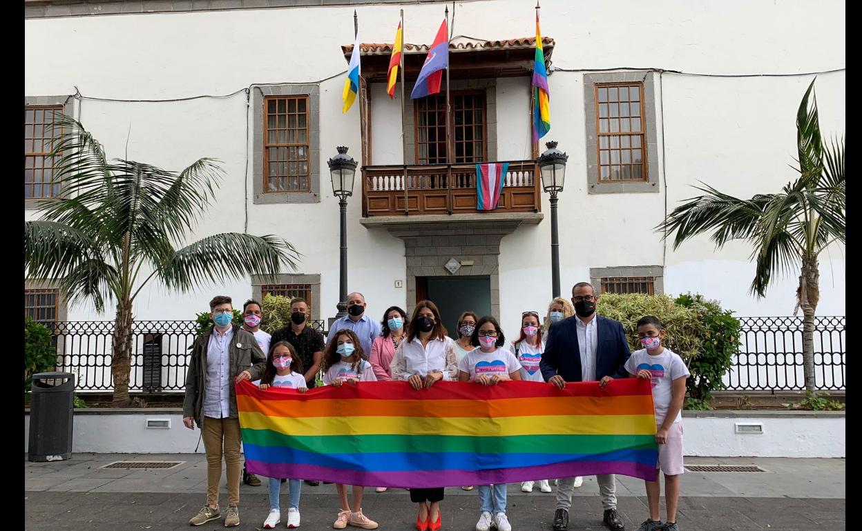Representantes de varios colectivos LGTBI+ posan junto a las autoridades municipales con la bandera del Orgullo delante de las Casas Consistoriales. 
