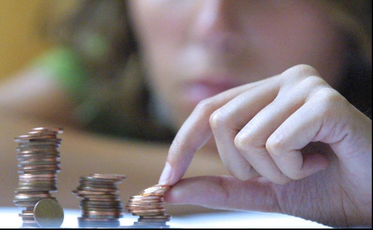 Mujer apilando monedas. 