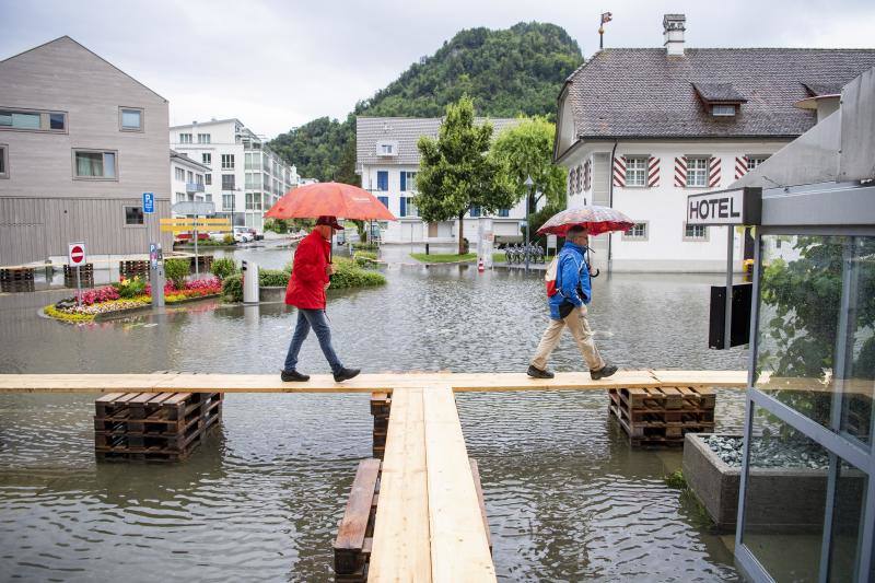 Vecinos caminan sobre tablas de madera creados para facilitar el paso en la plaza central de municipio de Stansstad , en el cantón de Nidwalden, Suiza. 