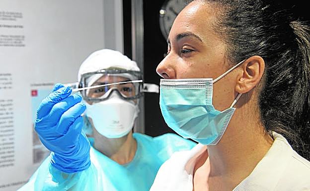 Una sanitaria realiza a una colega un exudado nasofaríngeo en un control rutinario en el punto de toma de muestras del Museo Elder. 