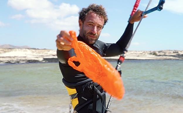 Deportista de kitesurf, con una bolsa. 