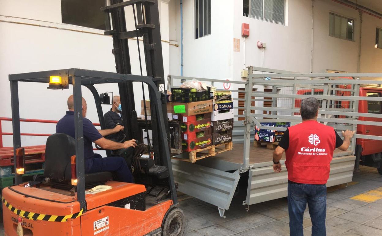 Diversos momentos de la entrega de alimentos este viernes. El alcalde y el párroco de Teror estuvieron en Cáritas recibiendo a los municipios. 