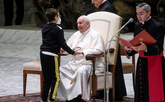 El Papa coge las manos del niño. 