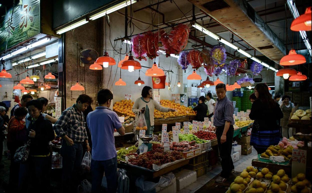 Gente comprando fruta en un mercado Hong Kong, China. 