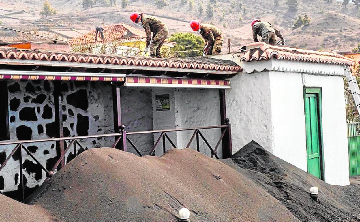 Militares del Ejército de Tierra retiran la ceniza de un tejado. 