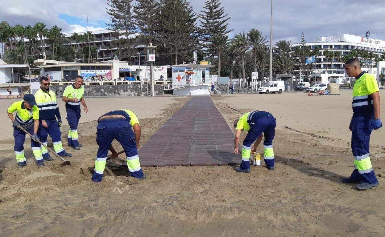 Colocación de una de las nuevas pasarelas para personas con movilidad reducida en Maspalomas. 