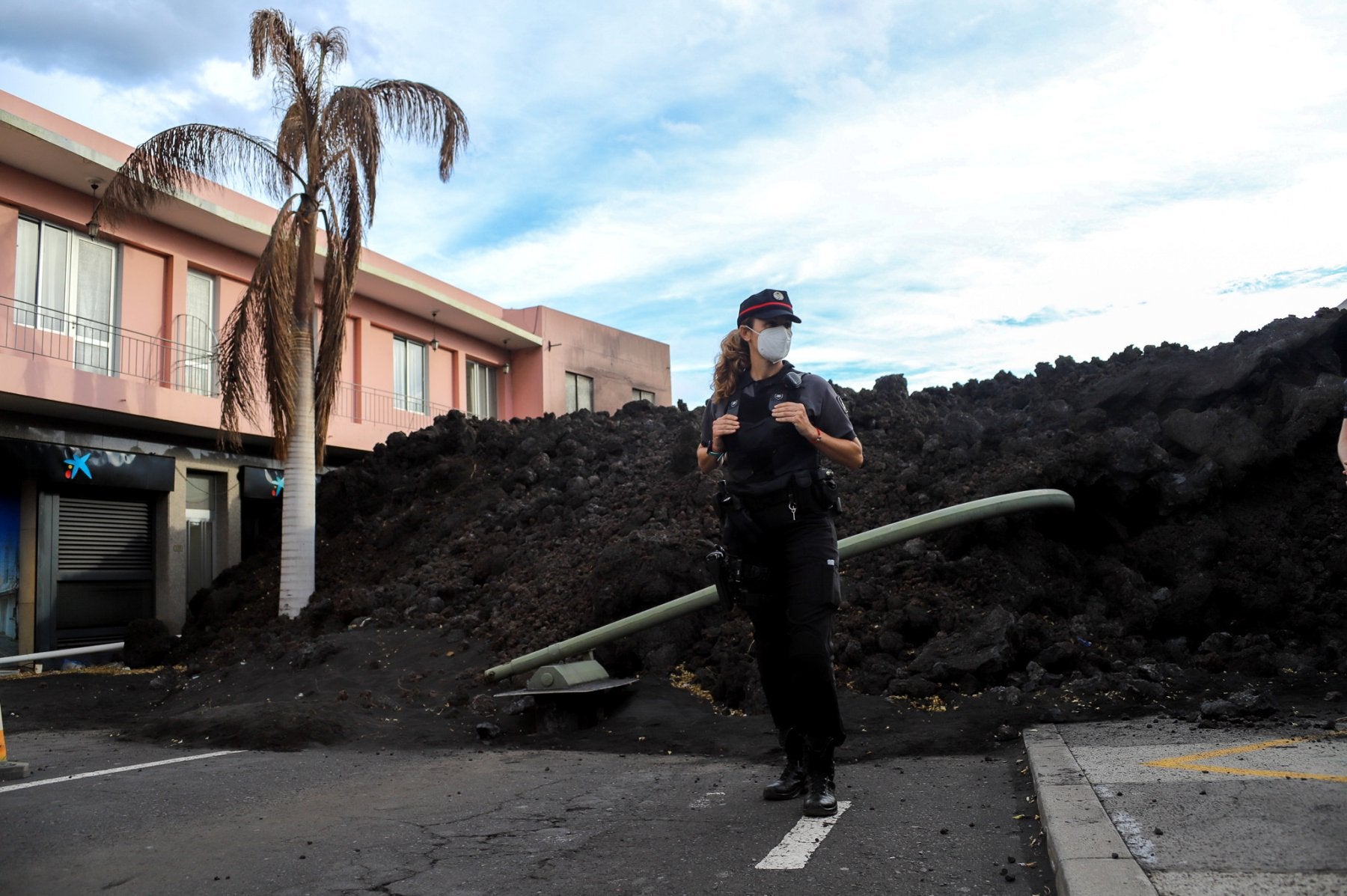 Vigilancia.Una agente de la policía canaria en el perímetro de seguridad de una colada. Arriba, el volcán apagado. 