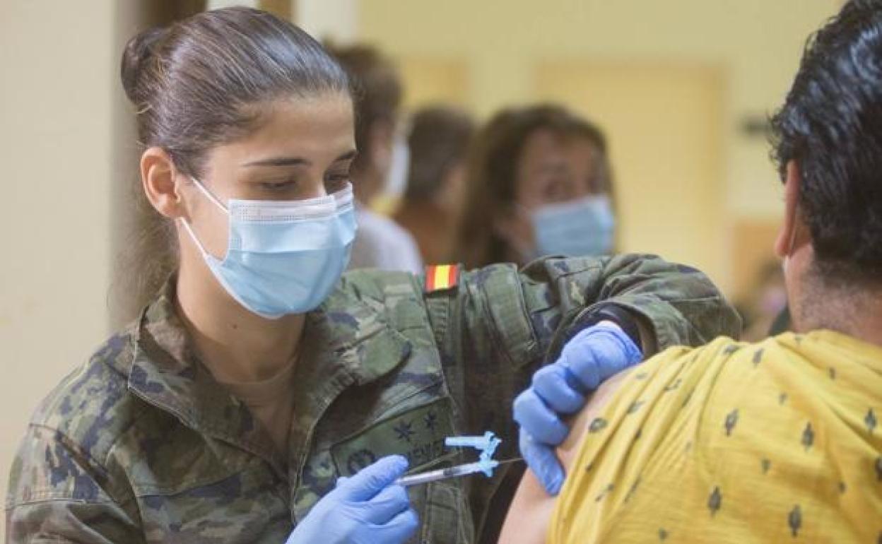 Una sanitaria militar vacuna a un ciudadano. 