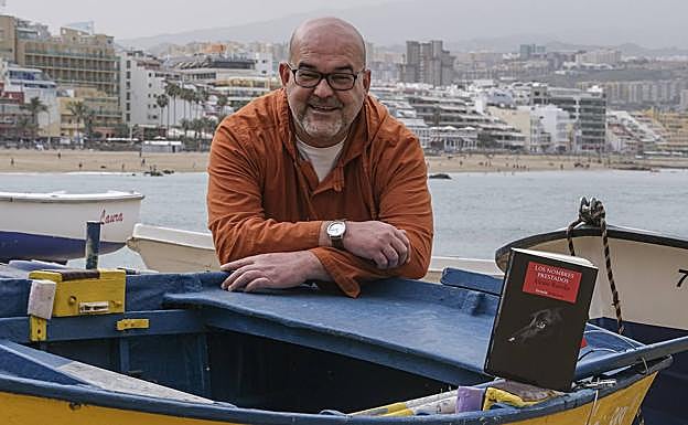 Alexis Ravelo, con un ejemplar de su nueva novela a la derecha, este viernes en Las Canteras. 