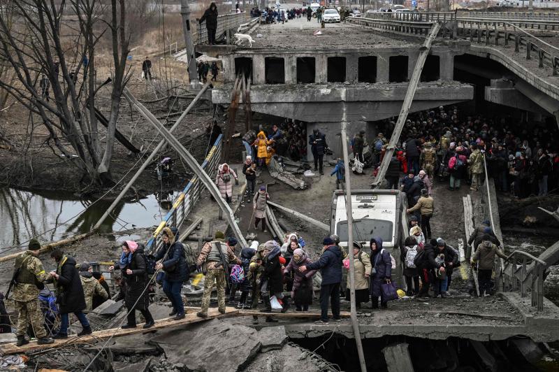 Soldados ucranianos ayudan a la población a cruzar un puente destruido tras los bombardeos en la ciudad de Irpin.