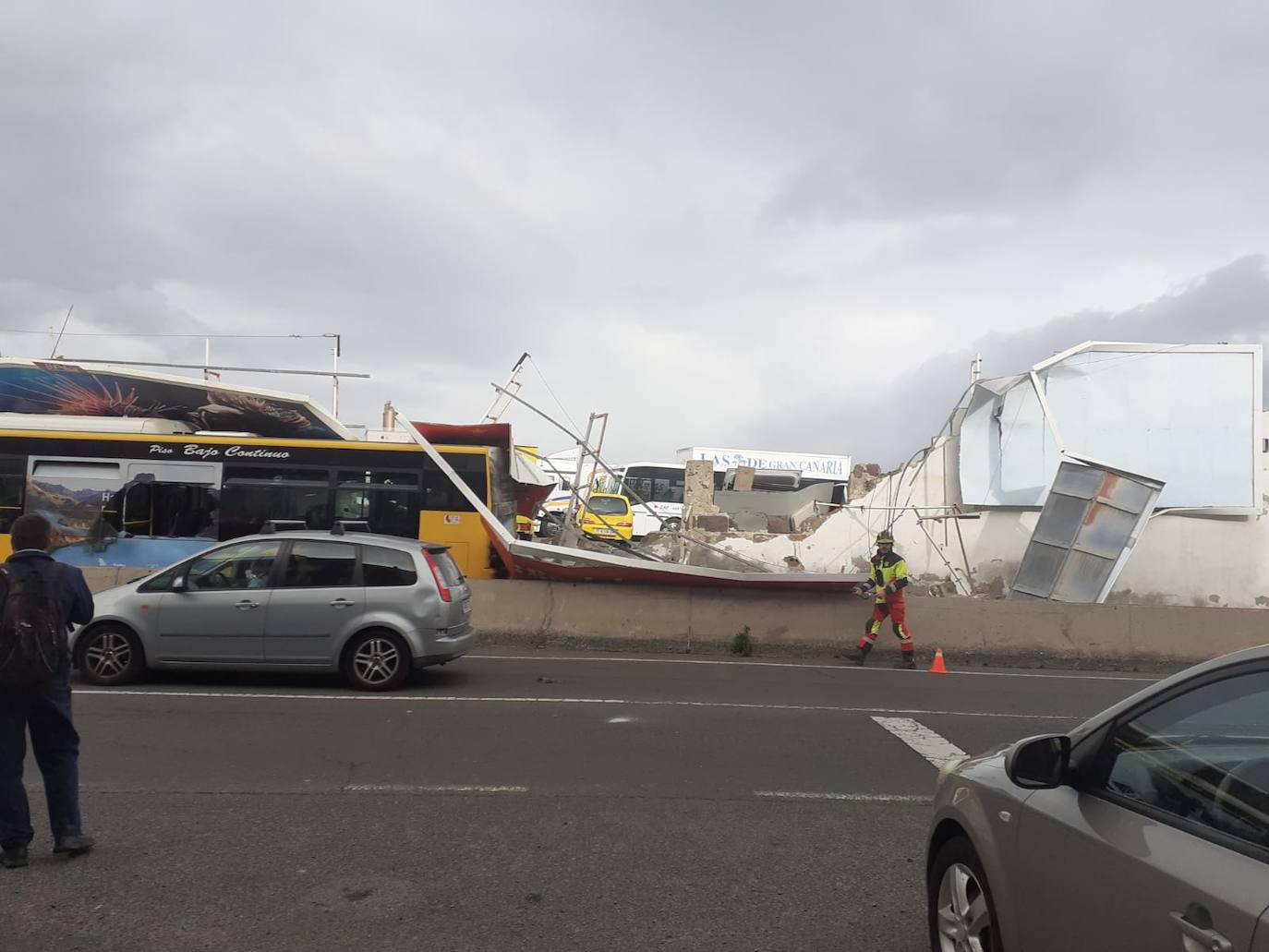 Imagen principal - Cae un muro con una valla publicitaria sobre una guagua en El Cardón