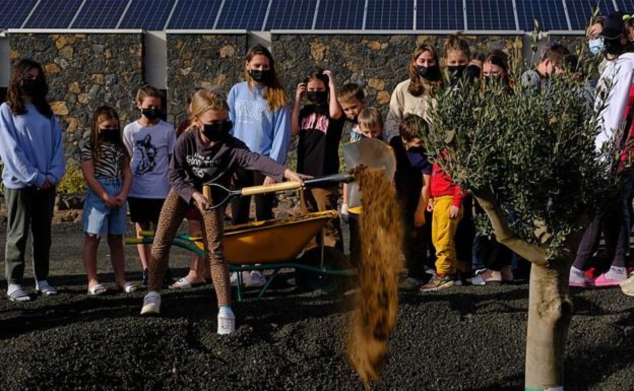 Una de las niñas echa una pala de tierra en presencia de la alcaldesa y del resto de menores ucranianos. 