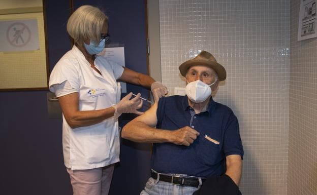 Imagen de archivo de una sanitaria revacunando a un hombre mayor contra la gripe y la covid. 