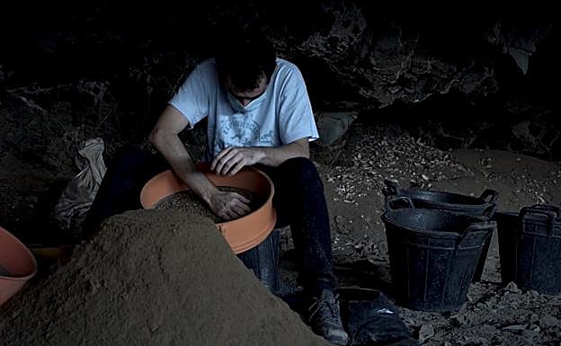 Uno de los técnicos de Arenisca cierne la arena de la cueva. 