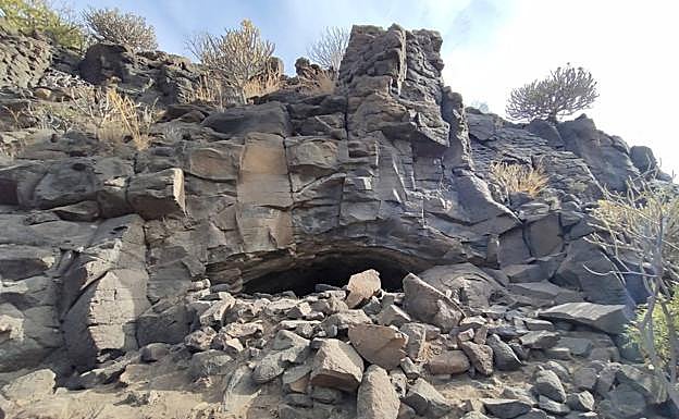 Imagen principal - Acceso de la cueva, zona delimitada en el interior y uno de los trabajadores en lo alto del talud. 