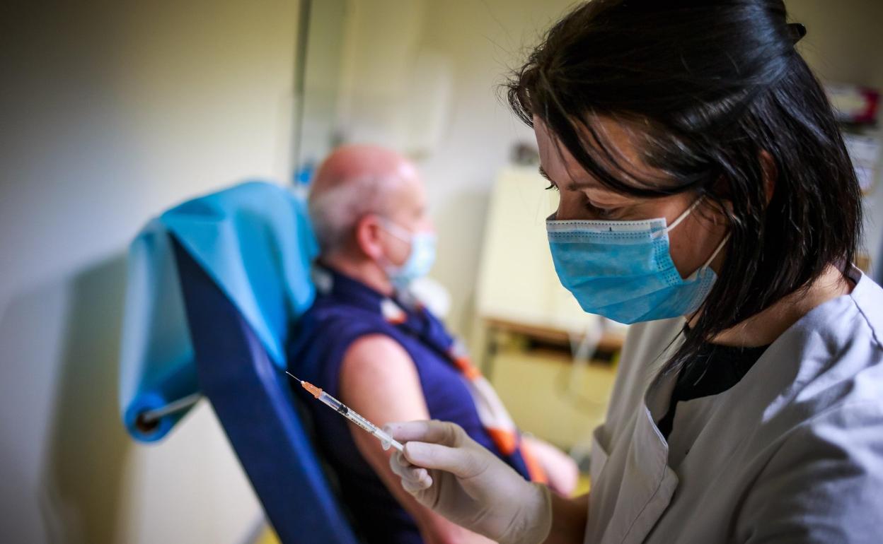 Un enfermera se prepara para vacunar a una persona de covida. 