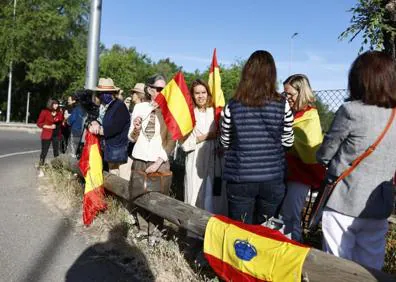 Imagen secundaria 1 - Un grupo de personas espera la llegada del Rey emérito a la Zarzuela con banderas de España.