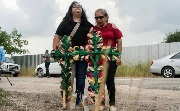 Dos mujeres colocan cruces y velas en el lugar donde fueron hallados muertos decenas de migrantes dentro de un camión en Texas.