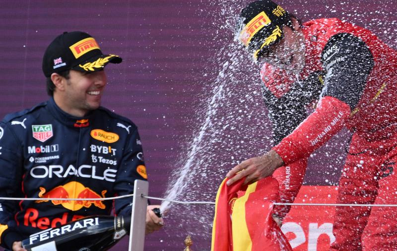 El piloto de Red Bull Sergio Pérez lanza champagne a Carlos Sainz.
