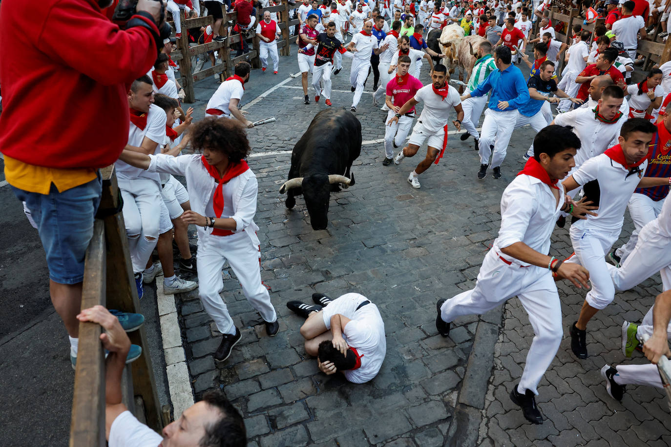 Un mozo cae delante de un toro en el sexto encierro de San Fermín.