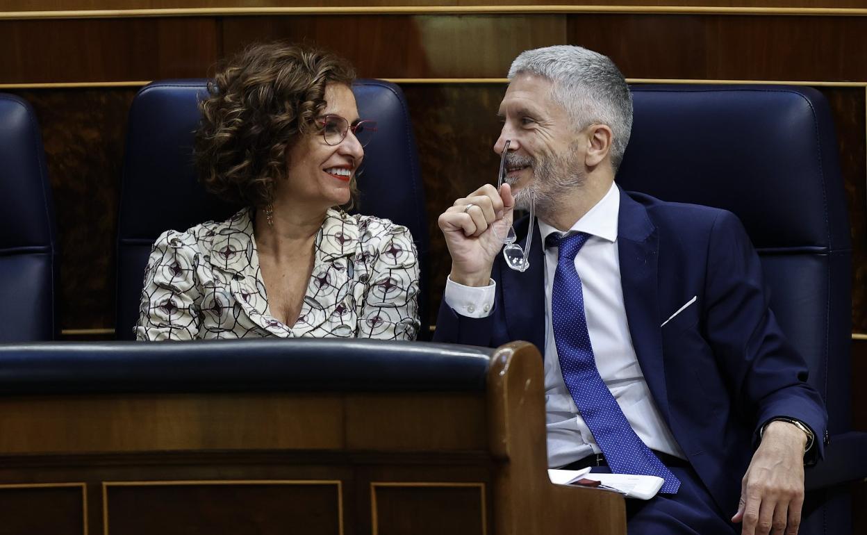 La ministra de Hacienda, María Jesús Montero, conversa con el titular de Interior, Fernando Grande Marlaska, en el pleno del Congreso. 