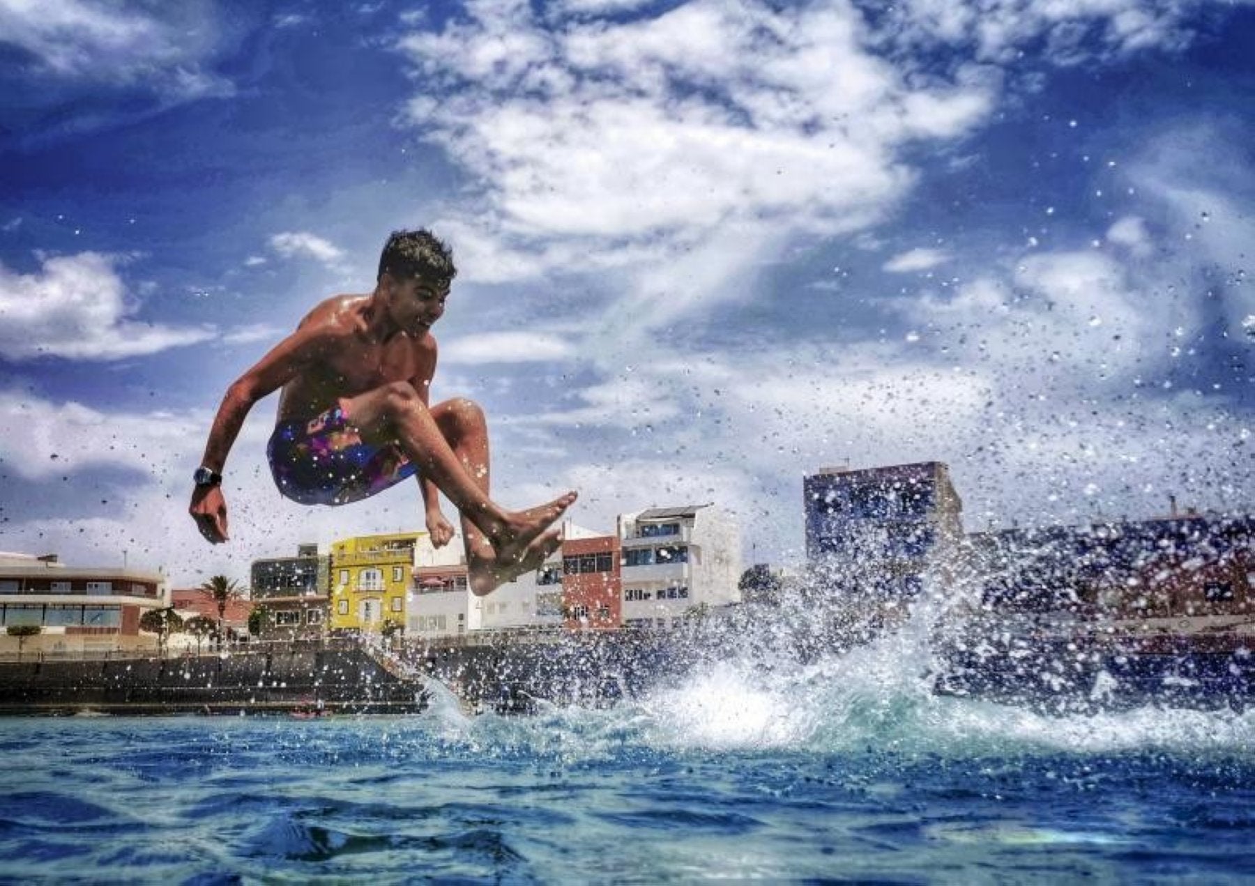 Un joven salta al mar en la playa de Arinaga. 