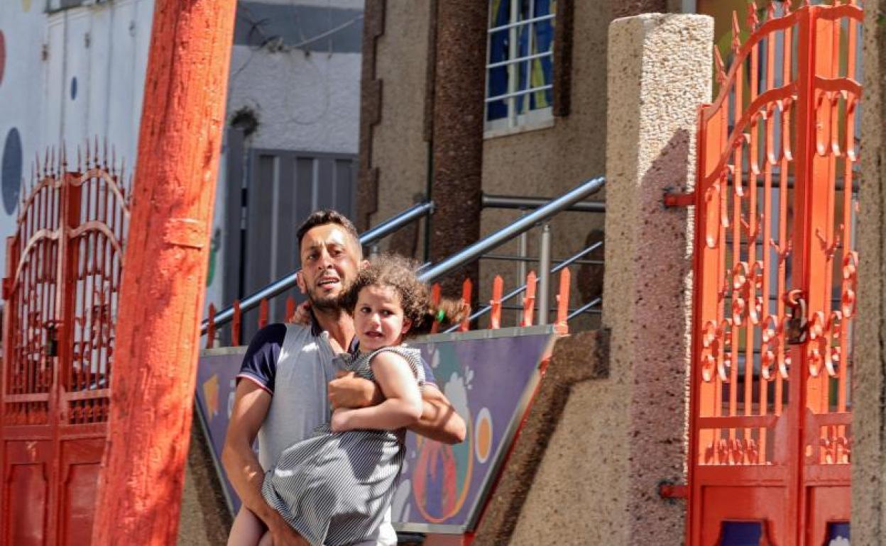 Un hombre corre con su hija en brazos hacia un refugio durante un bombardeo en Gaza. 