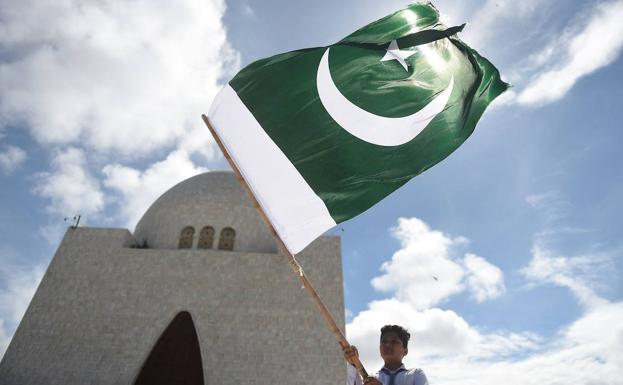 Un estudiante ondea la bandera nacional de Pakistán frente al mausoleo del fundador del país, Mohammad Ali Jinnah, en el 75 aniversario de su independencia.