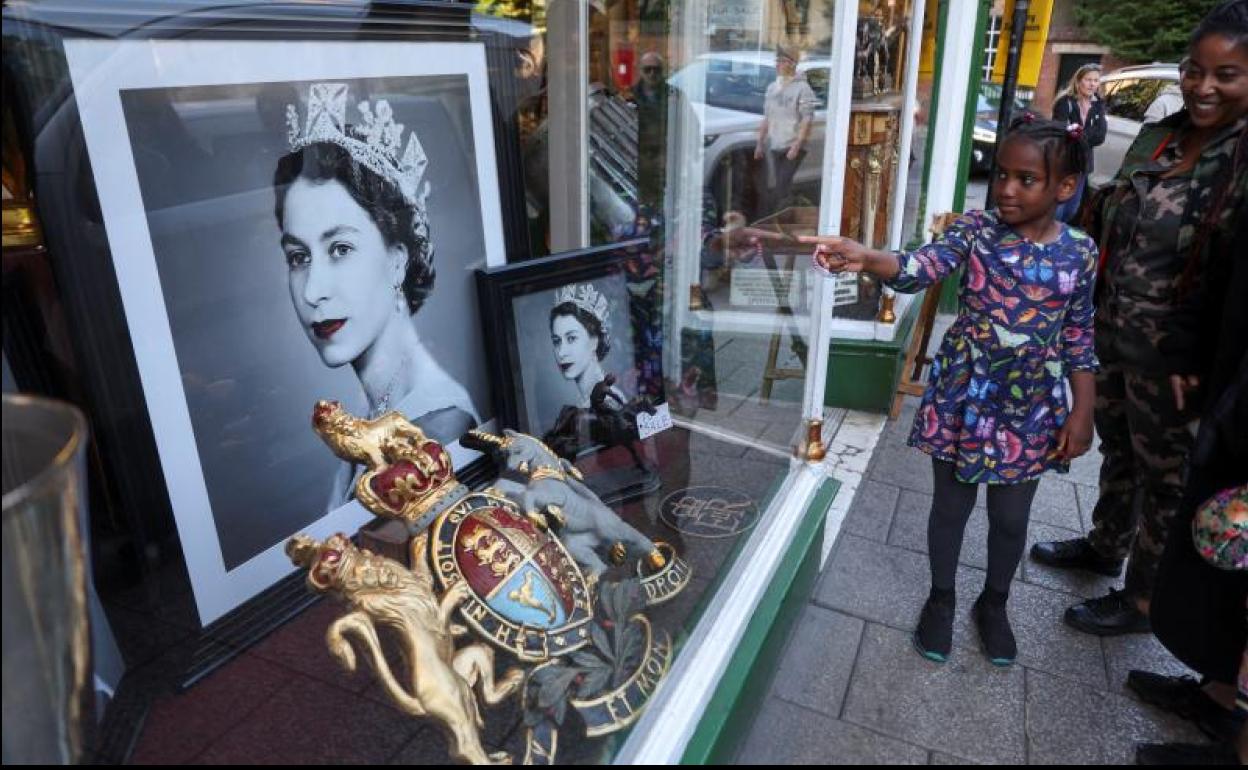 Una familia admira los retratos de Isabel II en el escaparate de un comercio en Londres. 