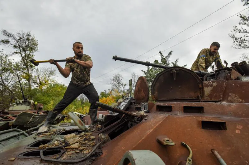 Dos soldados ucranianos desmantelan un carro de combate ruso