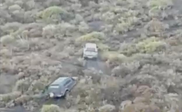 Dos vehículos atraviesan campo a través un espacio protegido. 