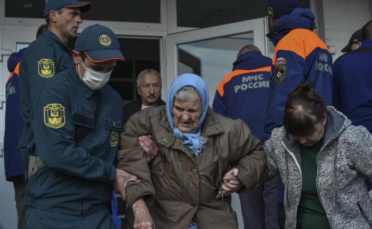 Socorristas rusos ayudan a evacuar a los residentes de una pensión geriátrica en la margen izquierda del río Dnieper, en Jerson.