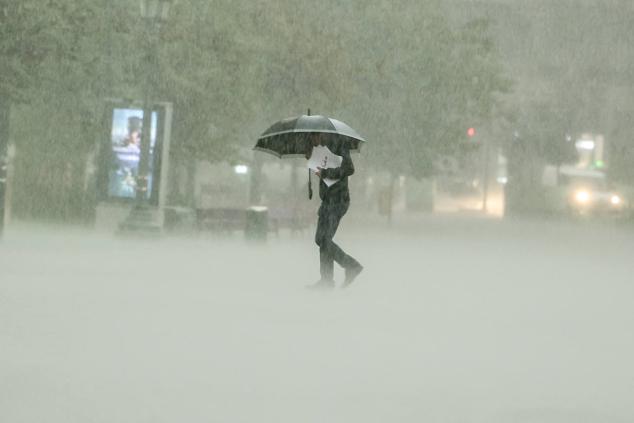 Un hombre camina bajo la lluvia torrencial en el centro de Valencia.