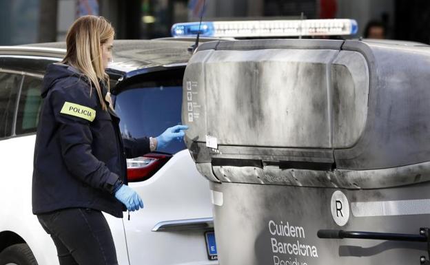 Una agente de los Mossos d'Esquadra este martes donde se ha hallado el cadáver mutilado de una persona dentro de una maleta en un contenedor.