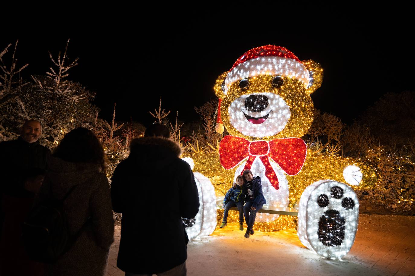 Dos niños posando con un oso navideño de gran tamaño en el Christmas Village en Port Bacares, Francia. 