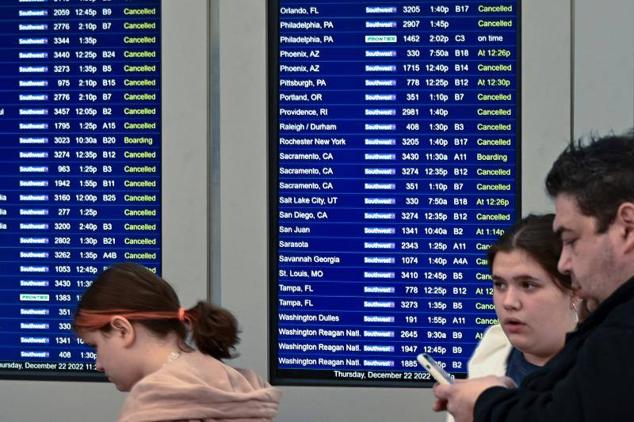 Viajeros consultan las notificaciones de salida mientras se acumulan las cancelaciones de vuelos a causa de un fenómeno meteorológico conocido como ciclón bomba que azota el Alto Medio Oeste, en el Aeropuerto Internacional Midway de Chicago, Illinois.