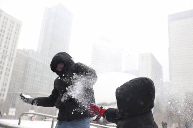 Andrés Garduno (izq.) participa en una pelea de nieve con su hijo en la pista de hielo del Millennium Park durante la tormenta invernal en Chicago, Illinois, el 22 de diciembre de 2022.