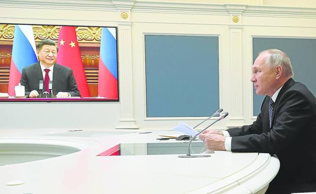 Putin, sentado en una sala del Kremlin, mantiene la videoconferencia con Xi Jinping./MIKHAEL KLIMENTYEV/efe
