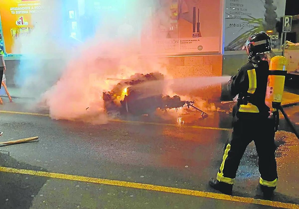 Un bombero apaga el incendio en un contenedor de basura, en una imagen de archivo.