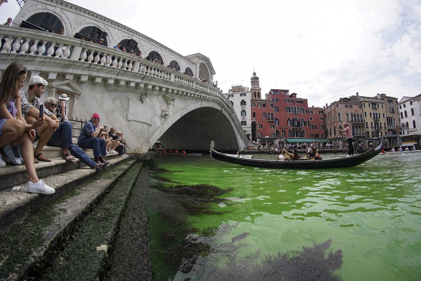 La gente observa una mancha de color verde fosforescenteen el Gran Canal cerca del Puente de Rialto, en Venecia. Los bomberos tomaron muestras de agua, mientras que el Prefecto de Venecia convocó una reunión urgente entre las fuerzas policiales de la ciudad, ya que aún se desconoce la causa.