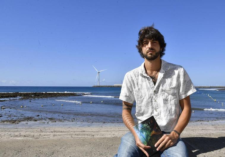 Carlos Mena, con su libro y la playa de Arinaga al fondo.